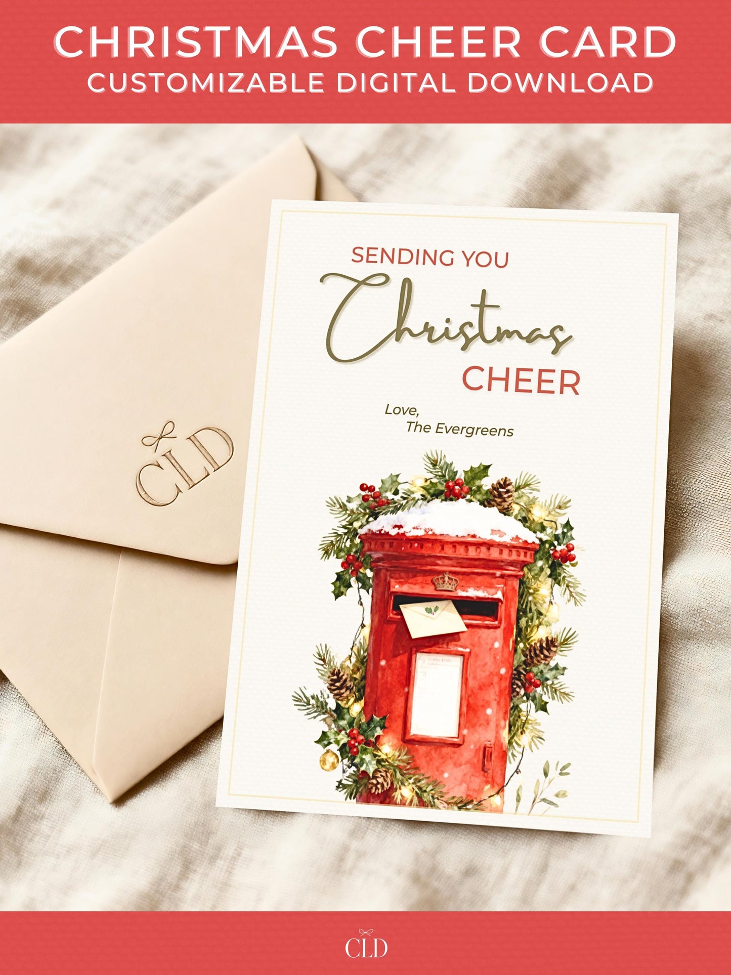 Printable Christmas card featuring a classic red British postbox surrounded by festive greenery, pinecones, and gold lights, with text reading ‘Sending You Christmas Cheer’. Displayed on a beige envelope with soft holiday lighting