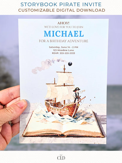 A hand holding a printed pirate birthday invitation showing a watercolor pirate ship sailing out of an open storybook, with paper-style waves, a cannonball, and the birthday details printed above in blue and brown text.