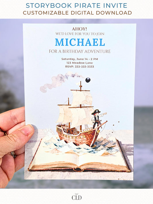 A hand holding a printed pirate birthday invitation showing a watercolor pirate ship sailing out of an open storybook, with paper-style waves, a cannonball, and the birthday details printed above in blue and brown text.