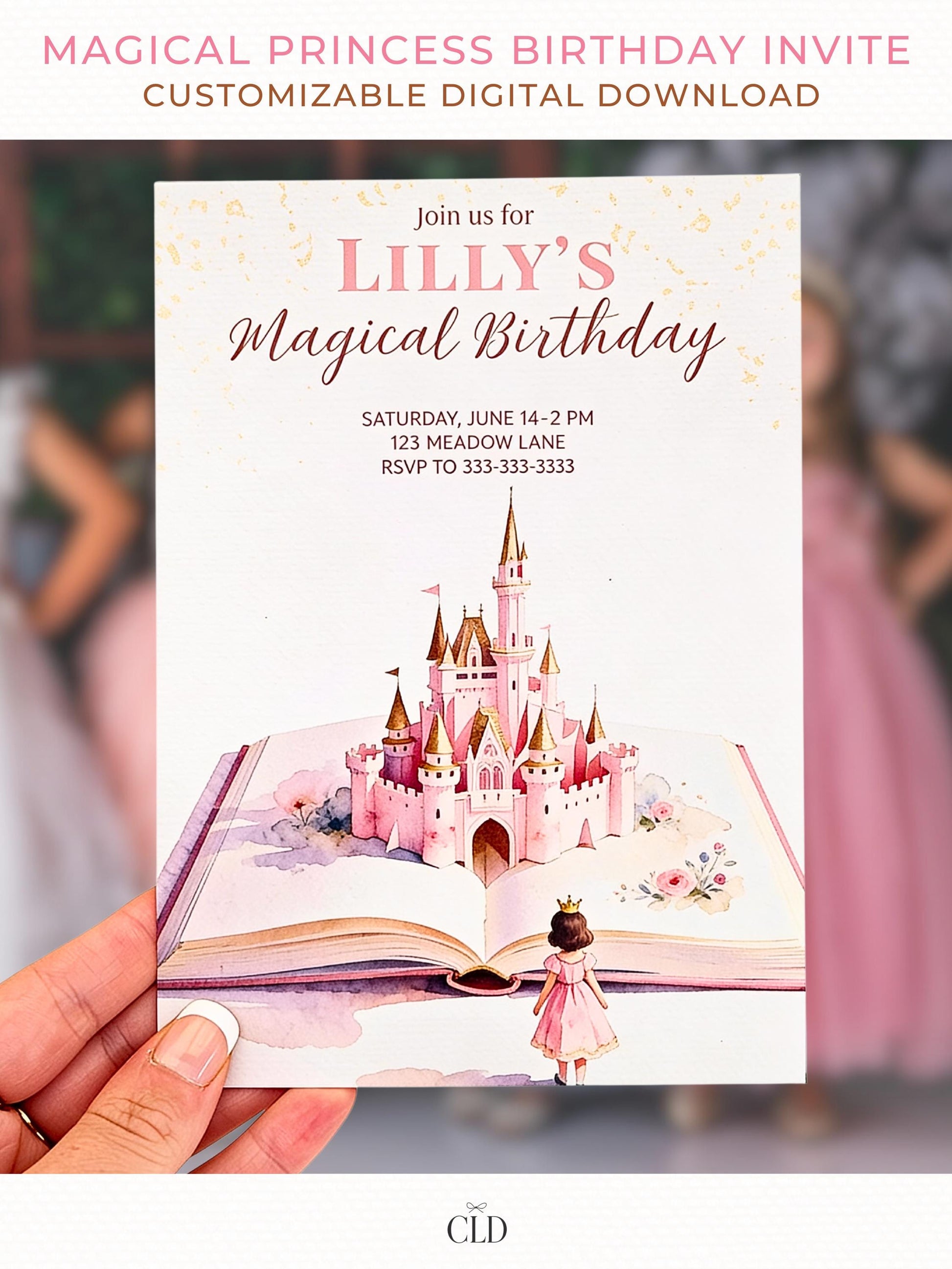 Close-up photo of a hand holding a printed fairytale-style princess birthday invitation featuring a pink castle rising from an open storybook, soft blush tones, and watercolor details. Light, magical background with warm tones.
