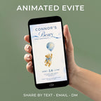 Animated teddy bear first birthday evite shown on a phone screen, featuring a soft watercolour bear holding a blue balloon with the number 1, on a dusty blue cloud background. Editable Canva template for a boy's first birthday party invitation, sent by text, email, or DM.